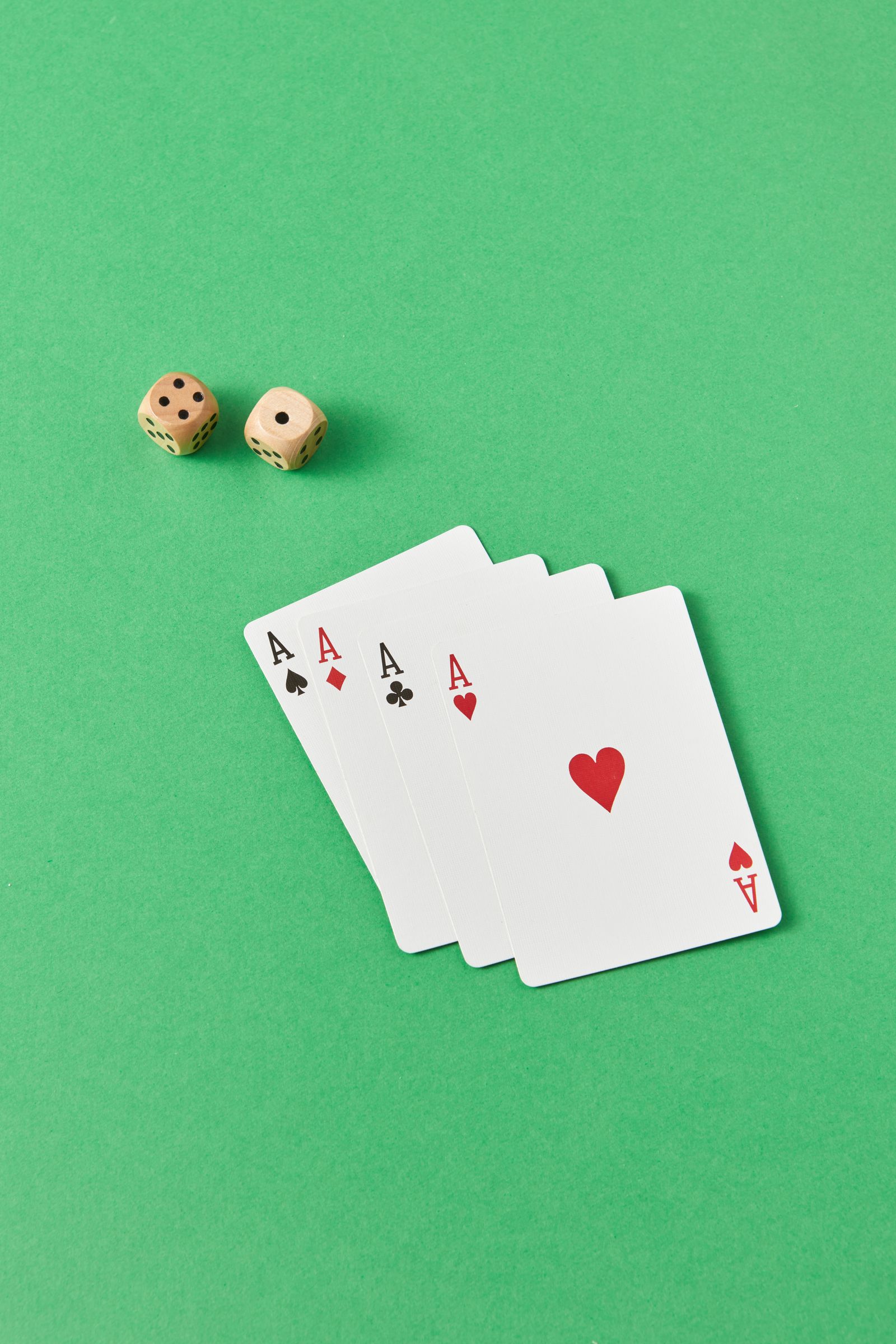 Four aces and dice on a green casino surface